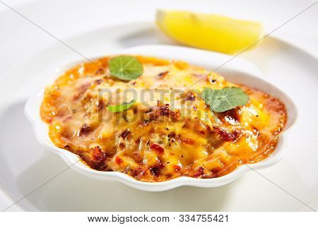 Seafood lasagna portion closeup. Italian traditional cuisine. Layered baked meal isolated on white background. Gourmet dish with pasta and cheese. Served and plated delicious food composition