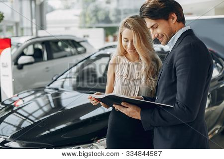 Stylish And Elegant Couple In A Car Salon