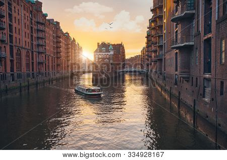 Famous Hamburg Warehouse District. Water Castle Palace And Tourist Boast In River In Sunset Golden L