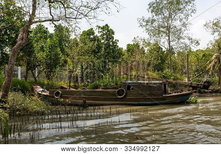 Tan Phong, Mekong Delta, Vietnam - March 13, 2019: Idle Bown Wooden Motorized Sloop Stuck At Green S