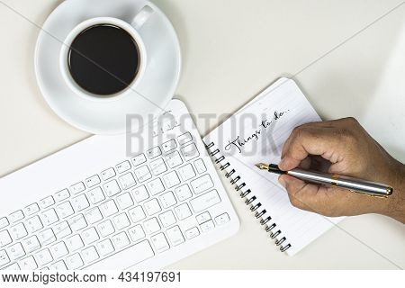 Working From Home Concept. Hand Writing In A Note Book, Keyboard And A Cup Of Coffee. Selective Focu