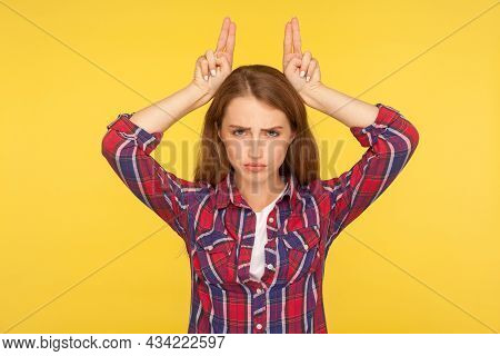 Im A Cow. Portrait Of Angry Menacing Ginger Girl In Checkered Shirt Showing Bull Horns On Head, Thre