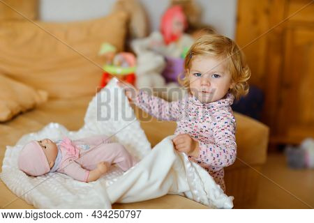 Adorable Cute Little Toddler Girl Playing With Doll. Happy Healthy Baby Child Having Fun With Role G