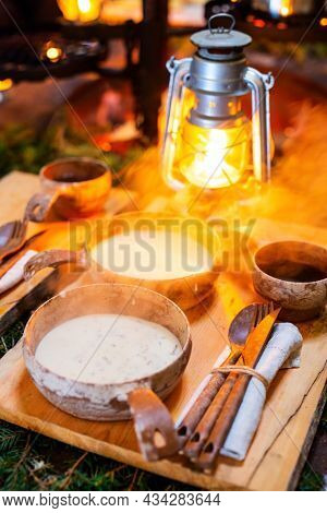 Delicious mushroom cream soup served in wooden bowls in lappish hut next to open fire