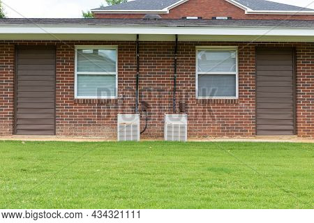 Exterior View Of A Generic Apartment Building With Older Model Hvac Heat Pumps, Twin Windows, Green 