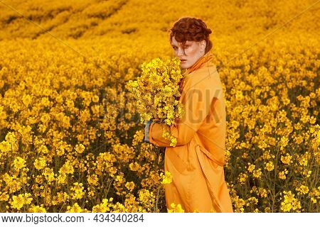 Portrait Of Red Haired Women Dressed In Trendy Fall Orange Trench Coat In Colourful Orange Field. Fa