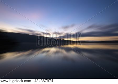 Blurry Background Of Sunrise Over The Lake. Colorful Morning Sky With The Water Reflection On Nature