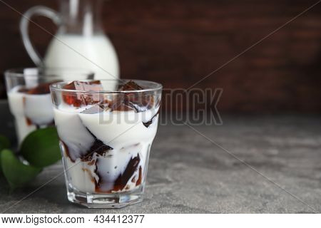 Glasses Of Milk With Delicious Grass Jelly On Grey Table, Closeup. Space For Text