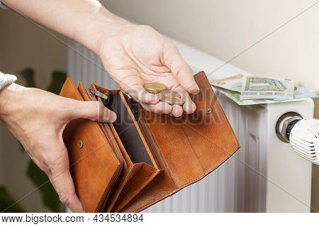 Womans Hand Takes Euro Money From Wallet And Places On Heating Radiator Battery With Temperature Reg