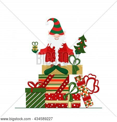 Cute Christmas Character. A Christmas Elf, A Gnome, Dressed In A Santa Claus Costume, Sits On A Pile