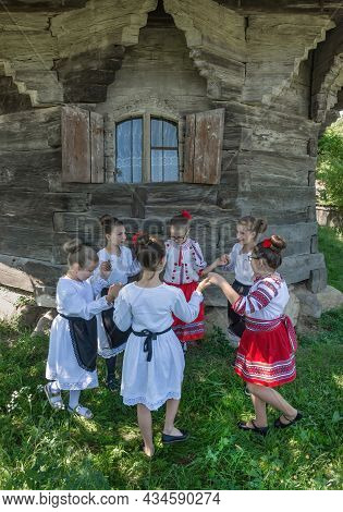 Salaj, Romania-may 13, 2018: Young Girls Wearing Traditional Folk Costumes Dancing In Front Of A Old