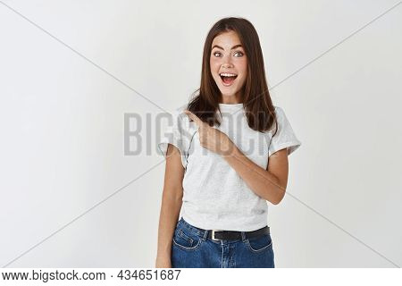 Amazed Young Woman Showing Banner, Pointing Finger At Upper Left Corner Copy Space And Staring At Ca