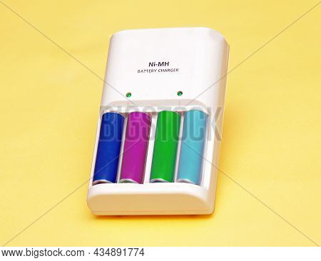 Colorful Lithium Batteries In Charger On Yellow Background