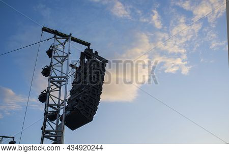 Line Array Speaker System Hanging From Pole During Daylight Performance. Sunset Blue Sky Background