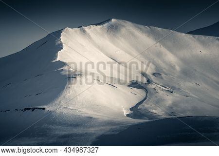 Mountain detail of a snowy peak looking along the ridge. Split toned, low key image. Svalbard, a Norwegian archipelago between mainland Norway and the North Pole
