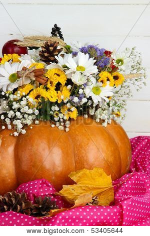 Beautiful autumn composition in pumpkin on table on wooden background