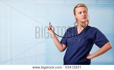 Pretty young nurse in hospital listening to empty copy space with sthetoscope