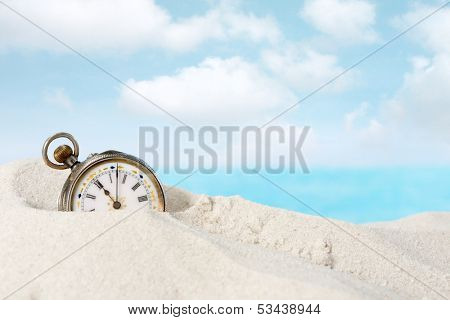 Old beautiful pocket watch lying in the beach sand