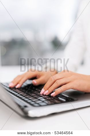 office, business, technology and internet concept - businesswoman using her laptop computer