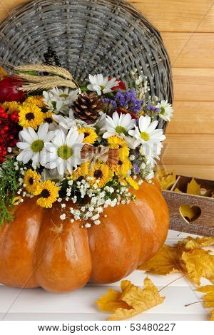 Beautiful autumn composition in pumpkin with bumps and decorative box on table on wooden background
