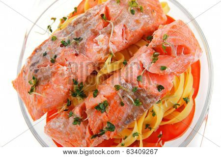 fresh fried natural pink salmon on italian traditional tagliatelle backed with tomato and vegetables isolated over white background