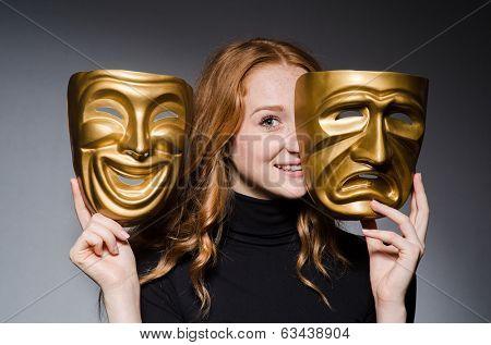 Redhead woman iwith masks in hypocrisy consept against grey background