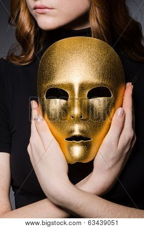 Redhead woman in hat  iwith mask in hypocrisy consept against grey background