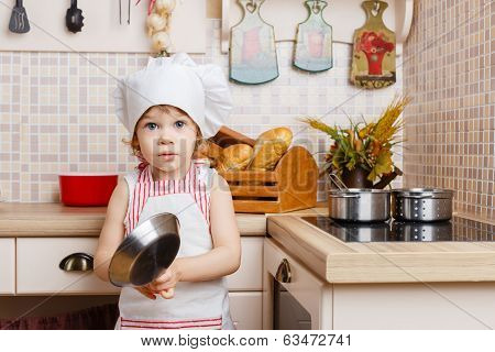 Little Girl In Apron In The Kitchen.