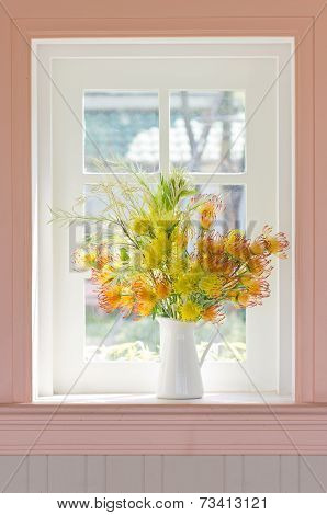Artificial Flowers In White Vase Beside White Window.
