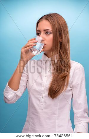 Portrait of young beautiful girl drinking clean water from a gla