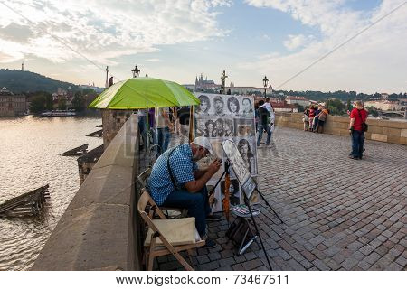 Cartoonist takes a break during his shift on Charles bridge, Prague