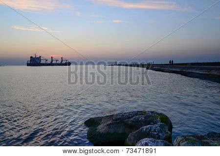 sunset at pier and a passing ship