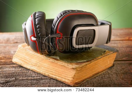 Headphones on the old book. Concept of listening to audiobooks.