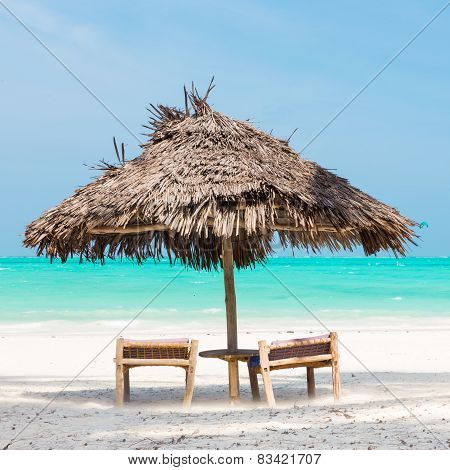 Two deck chairs and umbrella on tropical beach.