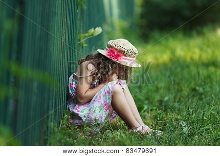 Sad Little Girl Sitting On Grass