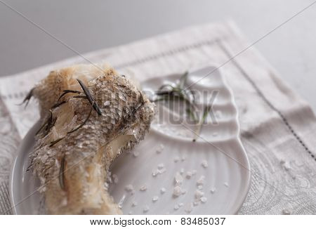 Cooked on steam grenadier fish with sea salt and fresh rosemary on white plate