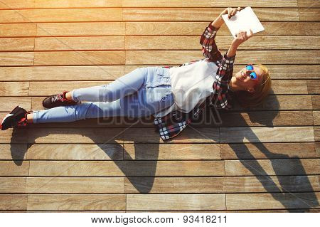 Young cute tourist girl taking self-ie with digital tablet camera outdoors