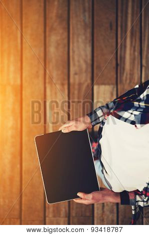 Portrait of a young attractive girl standing with a touch tablet on the wooden floor in a sunny day