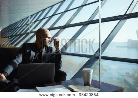 Side shot of handsome businessman pensively gazing out of the window thinking about the work plan