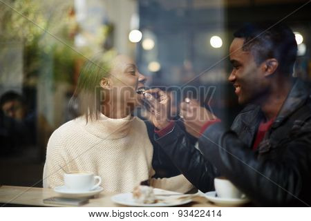 Beautiful couple having lunch man feeding his woman with dessert cake at their dating