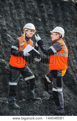 Two specialists examining coal at an open pit