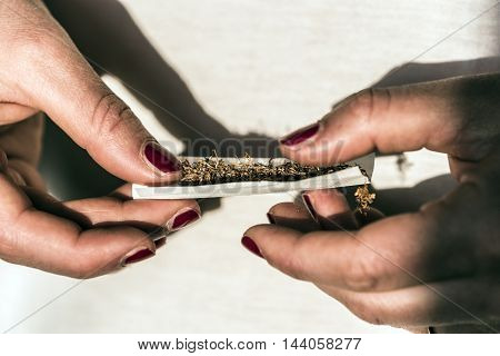 gilrl's hands rolling a tobacco cigaretteoutdoor closeup