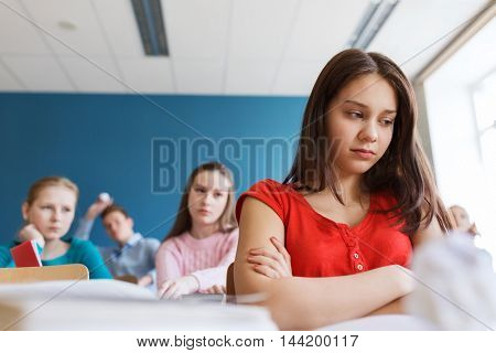 education, bullying, conflict, problem and people concept - students gossiping behind classmate back at school
