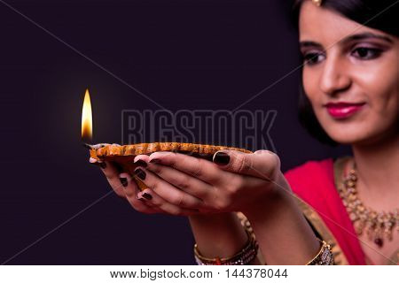 happy diwali greeting card showing indian beautiful Girl holding a diya on diwali festival, asian girl and diya, over black background