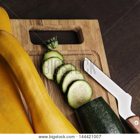 A fresh sliced zucchini on wooden kitchen desk with knife.wooden background.closeup