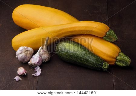 Two yellow big and medium and small green zucchini on wooden table.And garlic, chiveFamily of zuccini.