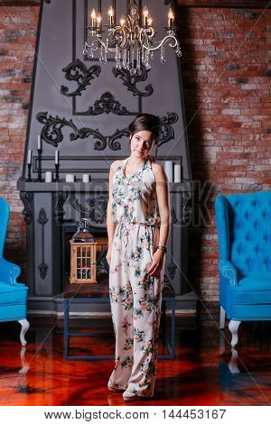 Beautiful woman with blue eyes and curly hair in dress on luxory interer background the fireplace chandelier. blue sofa.