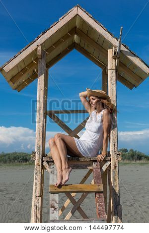 young attractive girl posing on a lifeguard tower on the beach