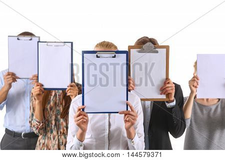 Team of businesspeople holding a folders near face isolated on white background .