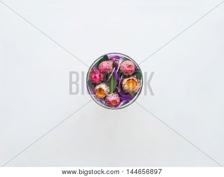 A glass with colorful flowers on a white background.